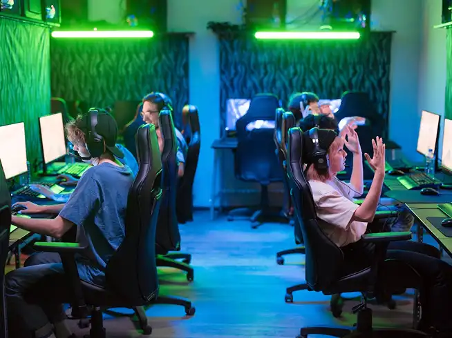 Moderne esports-gamekamer met meerdere spelers achter pc's onder groene neonverlichting, een competitieve multiplayer-omgeving.